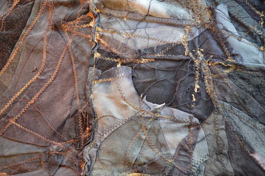 De binnenkant van de leren rugzak: een patchwork van leren lapjes met zichtbare stiksels en rafelranden. 