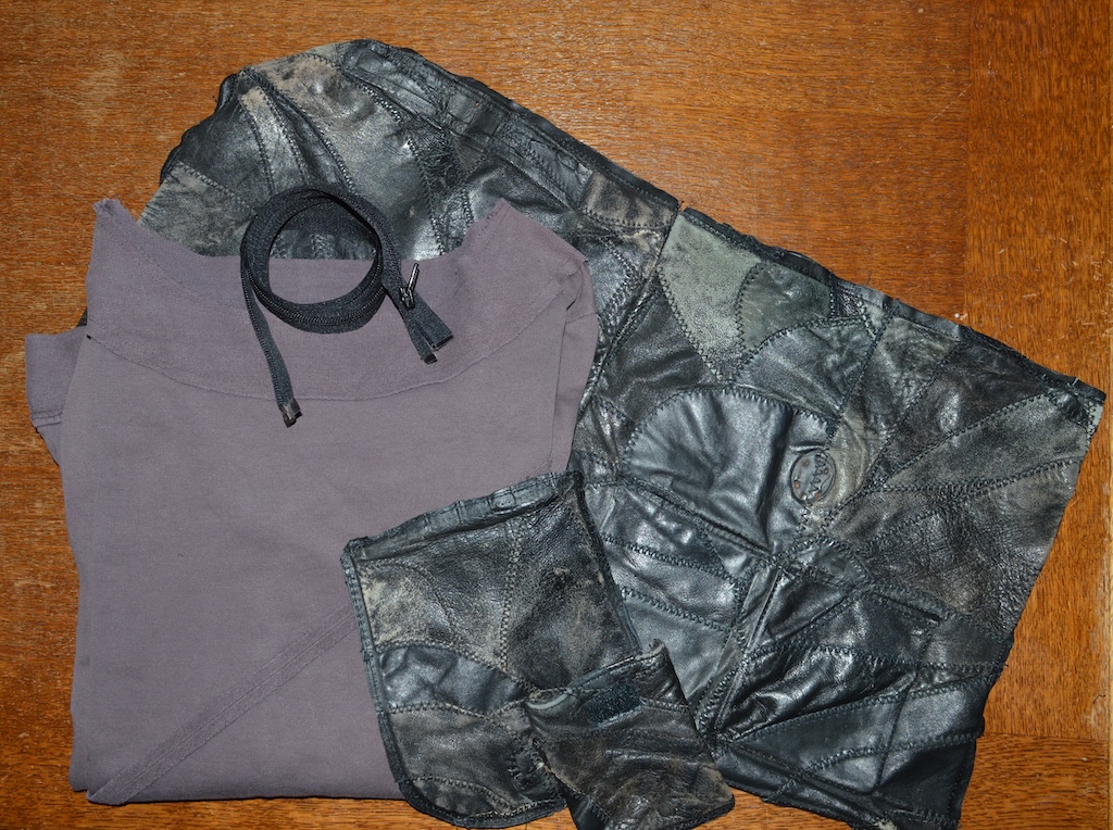 Materialen: een oude paarse trui van tricot, een opengetornde zwarte leren rugzak en een rits.